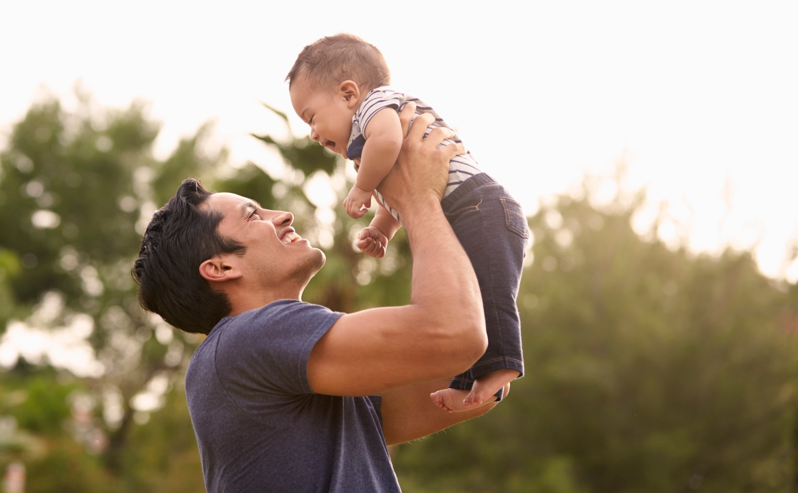 FINALmillennial hispanic father holding his little baby in the air in the picture id1094439300
