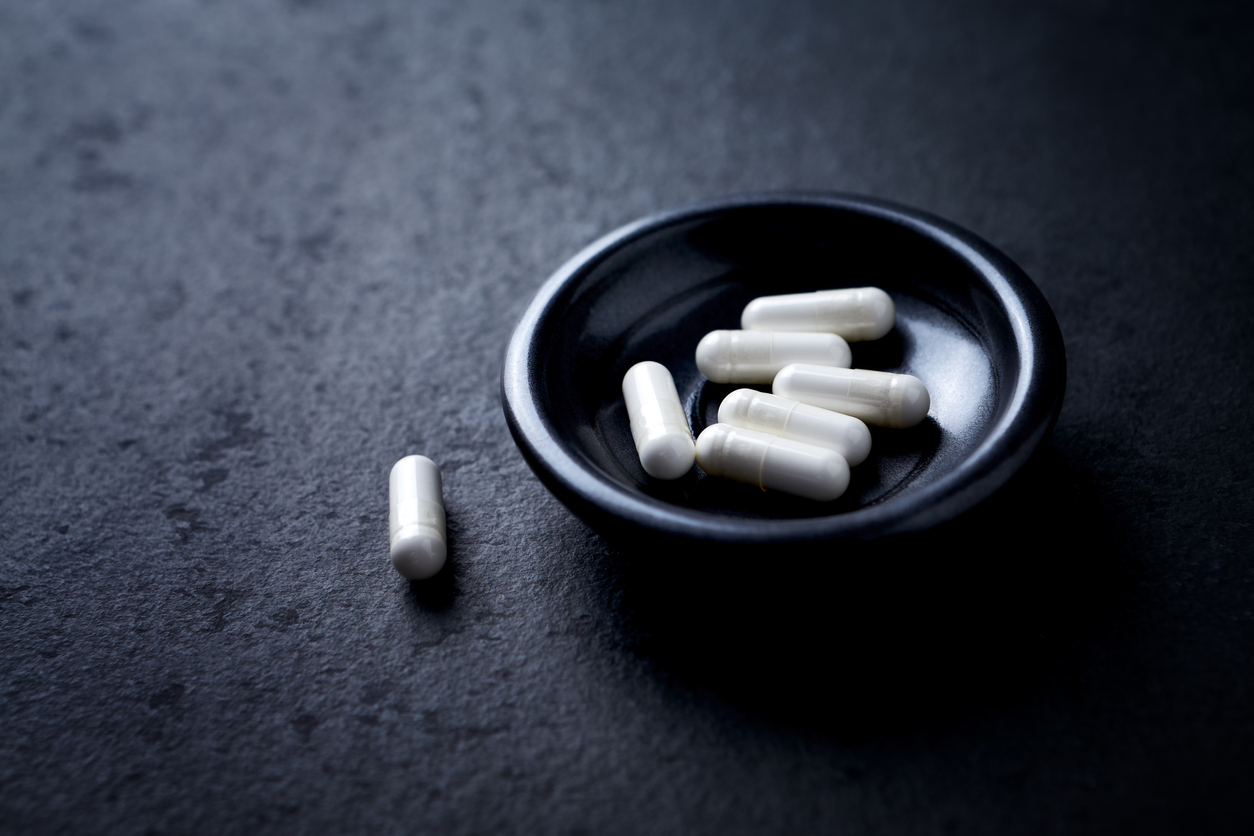 Arginine capsules. Bodybuilding food supplements on dark stone background. Close up.