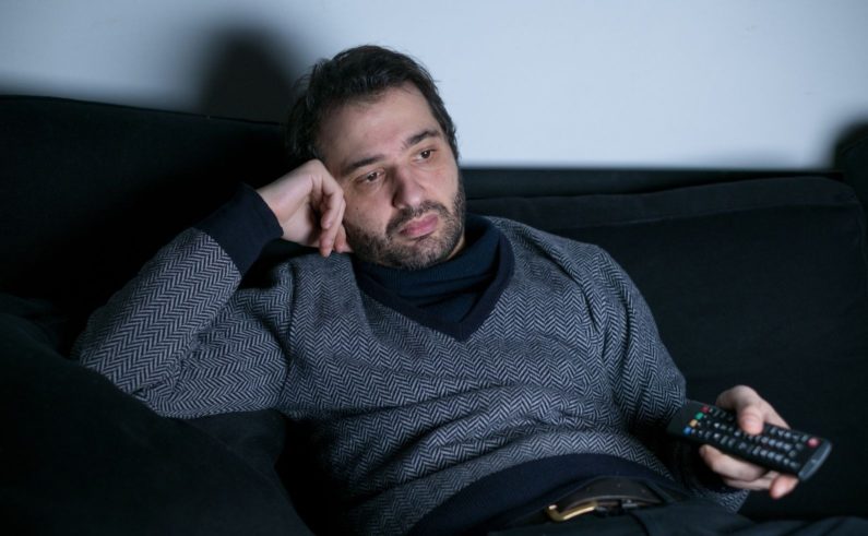 Man watching television at night lying on the couch