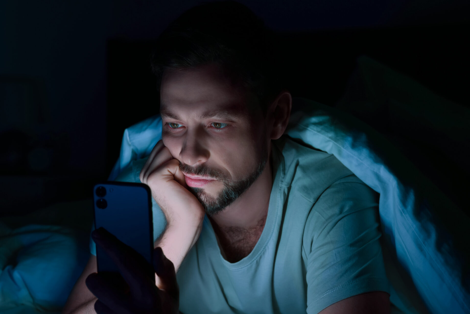 Man using smartphone in bed at night. Internet addiction